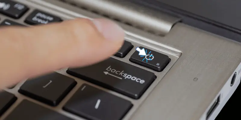 Finger-pressing the power button on a laptop
