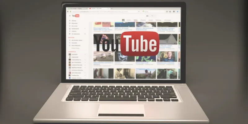 Laptop screen displays YouTube homepage
