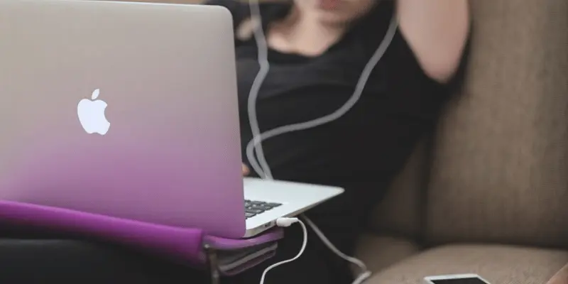 Person relaxing on a couch using a laptop with headphones on.