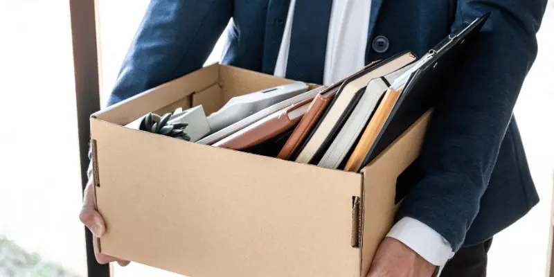 A professional carrying a laptop box of office belongings after resignation A professional carrying a laptop box of office belongings after resignation
