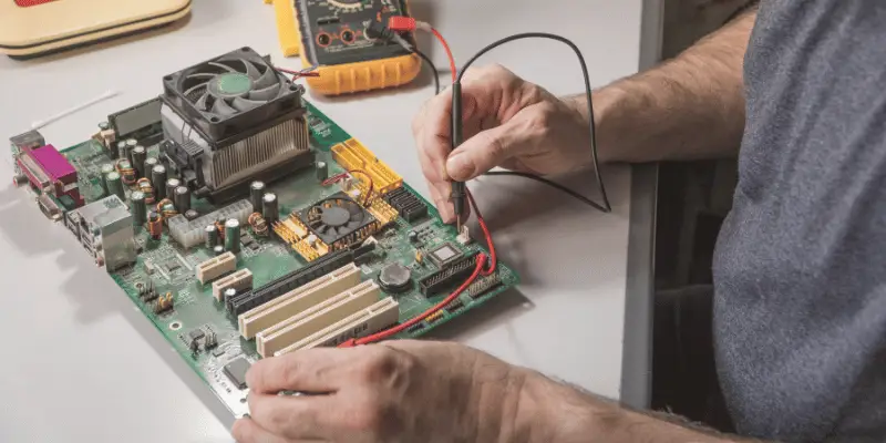 Technician repairing computer motherboard with precision tools Technician repairing computer motherboard with precision tools