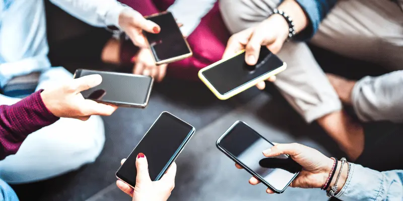 Multiple hands holding smartphones in circle formation showing modern mobile device usage and social interaction