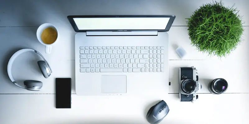 Laptop setup with coffee, headphones, and camera
