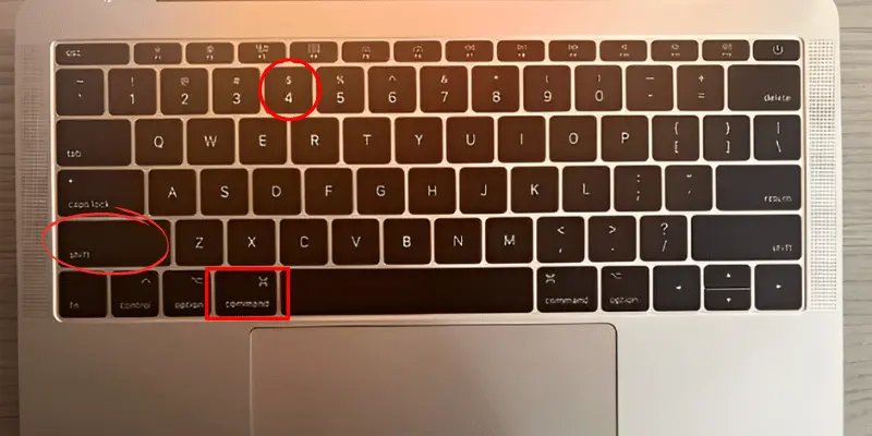 Highlighted Command, Shift, and 4 keys on a MacBook keyboard for taking screenshots.
