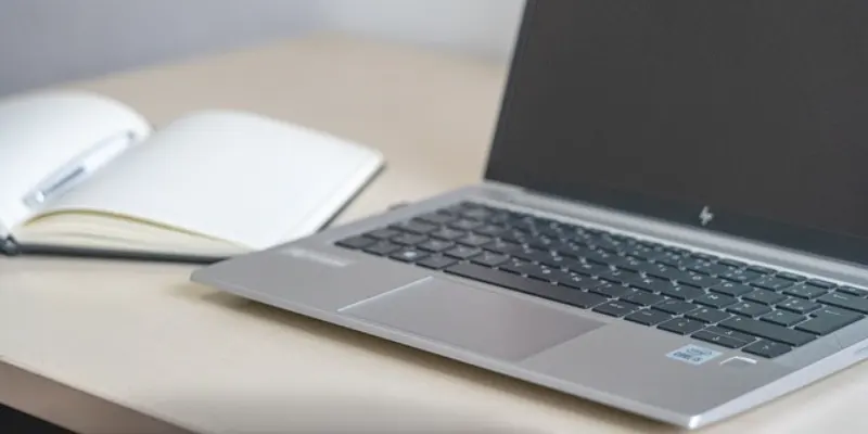 Open laptop and empty notebook on an office desk.