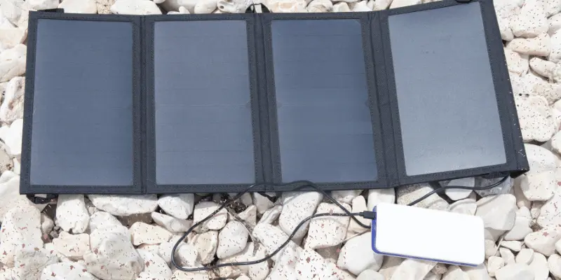 Foldable solar panel and power bank setup on rocks for outdoor charging